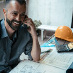 Restoration business owner talking on the phone while analyzing company profit.