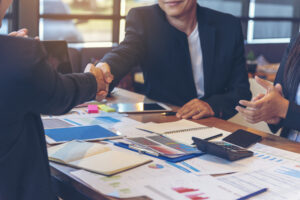Restoration business owner shakes hand with restoration claims management representative.