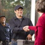 Restoration contractors shake hands with a satisfied customer in her doorway