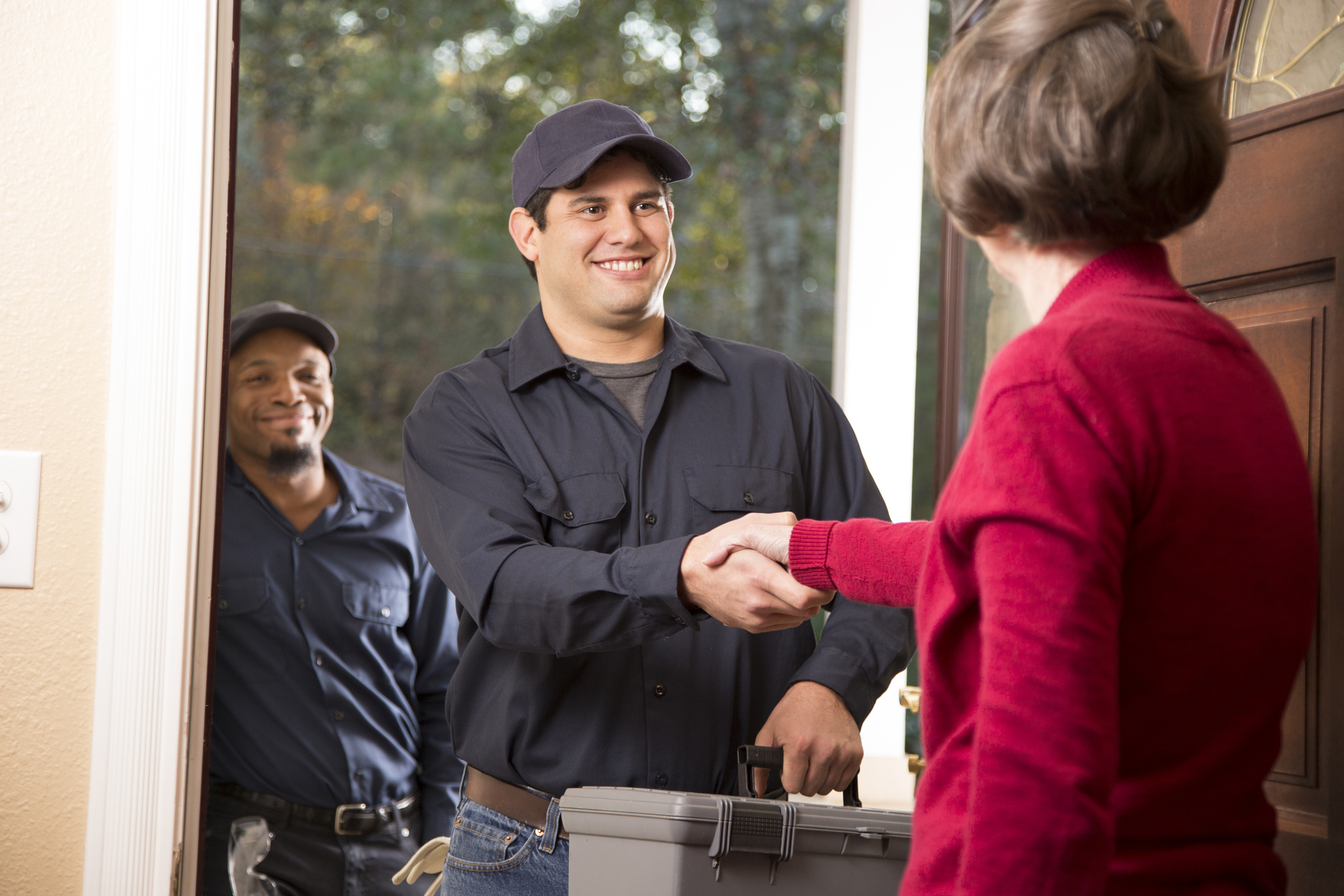 Restoration contractors shake hands with a satisfied customer in her doorway