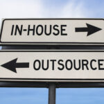 Street signs representing the decision between outsourcing a role or handling it in-house
