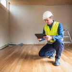 A restoration technician using a tablet to collect documentation on site before an appraisal.