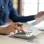 A restoration contractor reviews finances while using a calculator